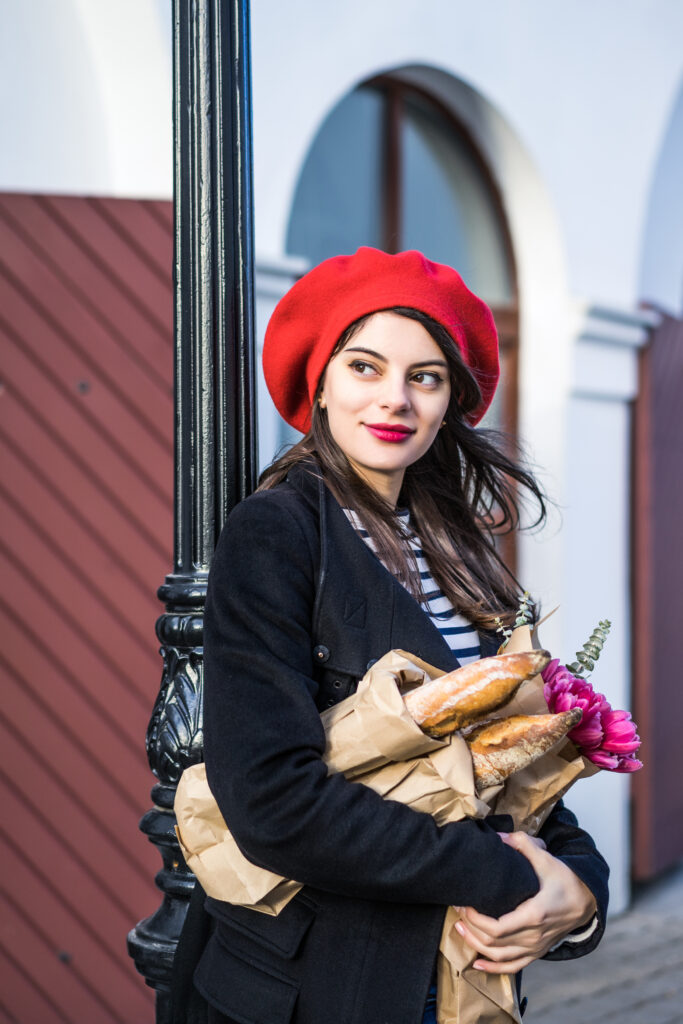 Femme francaise brune avec béret rouge portant des baguette